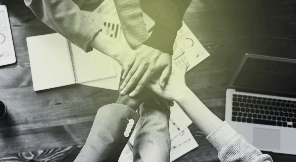 hands stacked over a desk with a computer on it