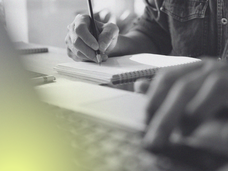 person on laptop writing in notebook